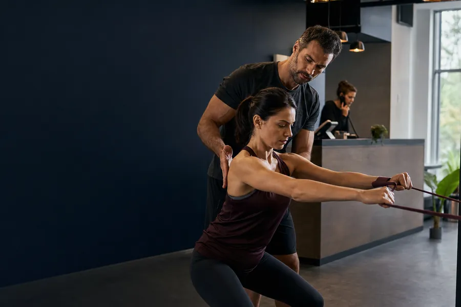 Personal trainer καθοδηγεί ασκούμενη σε σύγχρονο ευρωπαϊκό γυμναστήριο